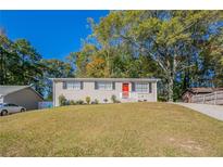 Ranch style home with red door and well-manicured lawn at 6230 Kensington Ct, Austell, GA 30106