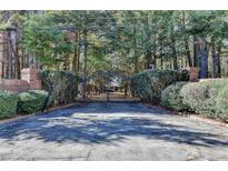 Brick pillars and wrought iron gate lead to a home nestled among the trees at 2701 Stilesboro Nw Ln, Acworth, GA 30101