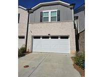 Modern townhome with gray and beige brick exterior, featuring a white garage door at 1702 Villageside Ct, Lawrenceville, GA 30043