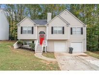 Two-story house with a red door, two-car garage, and landscaped yard at 6943 Fairway Trl, Austell, GA 30168