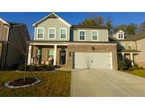Two-story home with brick and siding, a two-car garage, and a landscaped front yard at 573 Auburn Crossing Dr, Auburn, GA 30011