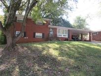 Brick ranch house with carport, large yard, mature trees, and landscaping at 1318 Shoreham Dr, Atlanta, GA 30349