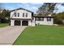 Brick ranch home with 2-car garage, landscaped lawn, and large driveway at 2611 Kings Cir, Lawrenceville, GA 30044