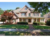 Brick two-story home with a front porch and landscaped lawn at 4496 Meadow Club Dr, Suwanee, GA 30024