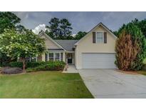 Charming ranch home with a yellow facade, landscaping, and a two-car garage at 3894 Potomac Walk Ct, Loganville, GA 30052