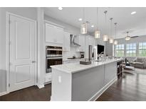 Modern kitchen with white cabinets, quartz countertops, stainless steel appliances, and an island at 223 Britten Pass, Alpharetta, GA 30009