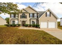 Two-story house with beige siding, two-car garage, and landscaping at 690 Lakewater View Ln, Stone Mountain, GA 30087