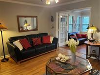 Living room with black leather sofa and sunroom access at 98 De Arc Nw, Atlanta, GA 30327