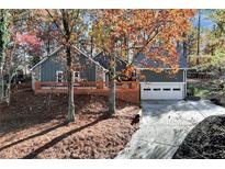 Gray house with stone accents, wooden deck, and attached garage; nestled among autumn trees at 9154 Branch Valley Way, Roswell, GA 30076