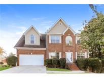Two-story brick home with a large white garage door and landscaping at 4815 Candy Cv, Lithonia, GA 30038