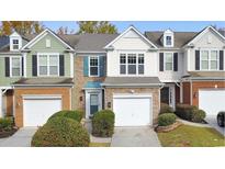 Three-unit townhome building with stone and siding, two-car garages, and landscaping at 247 Kigian Trl, Woodstock, GA 30188