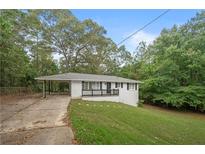 White brick ranch house with carport, black railings, and landscaped yard at 6650 Queen Mill Se Rd, Mableton, GA 30126