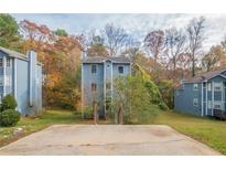 Three-story townhome with a gray exterior, situated on a grassy lot with trees at 4480 Joseph Dr, Snellville, GA 30039