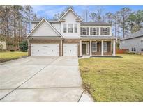Two story house with a three-car garage and landscaped yard at 2166 Leatherstone Dr, Powder Springs, GA 30127