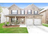 Brick two-story house with a two-car garage and landscaped lawn at 7843 Shertall St, Fairburn, GA 30213