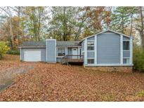 Gray house with attached garage and a yard full of autumn leaves at 9887 Live Oak Ct, Douglasville, GA 30135