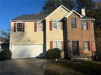 Two-story house with a brick and vinyl exterior, attached garage, and landscaping at 5750 Old Carriage Dr, Atlanta, GA 30349