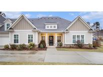 Beige two-story house with gray roof, landscaping, and a paved driveway at 141 Legends Way, Hiram, GA 30141