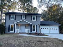 Two-story gray house with white trim, two-car garage, and landscaped yard at 1463 Martin Nash Sw Rd, Lilburn, GA 30047