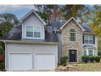 Two-story house with stone accents, two-car garage, and landscaped yard at 3579 Oakshire Se Way, Atlanta, GA 30354