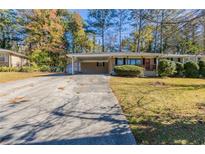 Ranch home with covered carport and well-maintained lawn at 6677 Songwood Dr, Austell, GA 30168