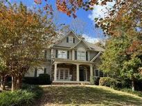 Two-story home with stone accents and covered porch, nestled among mature trees at 827 Registry Nw Ter, Kennesaw, GA 30152