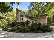 A charming two-story home nestled in a wooded setting, featuring a stone chimney and landscaping at 123 Cherry St, Roswell, GA 30075