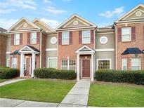 Brick townhome with 2-story elevation, landscaped lawn, and a charming front porch at 7512 Rutgers Cir, Fairburn, GA 30213
