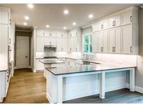 Spacious kitchen with island, white cabinets, and granite countertops at 11355 Bennett Ln, Johns Creek, GA 30097