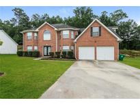 Brick house with two-car garage and landscaped lawn at 6899 Dalehollow Dr, Lithonia, GA 30058