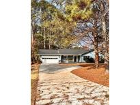 Ranch style home with attached garage, long driveway, and mature trees in the front yard at 2815 Highway 20 Se, Conyers, GA 30013