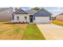 Two-toned house with white brick and blue siding, featuring a white two-car garage at 231 Orwell Dr, Social Circle, GA 30025