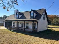 White house with brown roof, covered porch, and attached garage at 1350 Cedars Rd, Lawrenceville, GA 30045