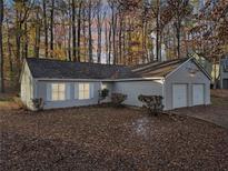 Ranch home with two-car garage, light gray siding, and a tree-filled lot at 3849 Greenbrook Dr, Douglasville, GA 30135