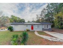 Charming ranch home with a red door and well-maintained lawn at 6103 Oakwood Sw Cir, Covington, GA 30014