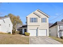 Two-story house with beige siding, two-car garage, and landscaped yard at 6422 Phillips Ct, Lithonia, GA 30058