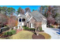 Brick home with landscaped yard, large driveway, and architectural details at 2015 Lake Shore Lndg, Alpharetta, GA 30005