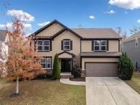 Two-story house with brown and beige siding, a large garage, and landscaping at 904 Berry Ct, Canton, GA 30114