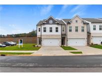 Two-story townhome with white and brick exterior, two-car garage, and landscaping at 859 Eagle Avenue, Riverdale, GA 30247