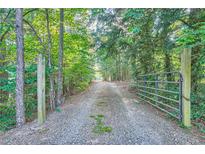 Gravel driveway leads through a gated entrance to the property at 1565 Dr Bramblett Rd, Cumming, GA 30028