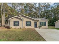 Newly constructed home with gray siding, dark trim, and a landscaped lawn at 7133 Pineview Sw Dr, Covington, GA 30014