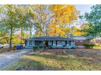 Charming ranch home with a red door and mature trees in the front yard at 2363 Dabney Ter, Atlanta, GA 30344