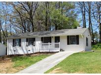 Newly renovated ranch home with white brick exterior, landscaped yard, and driveway at 6325 Westbury Rd, Riverdale, GA 30274