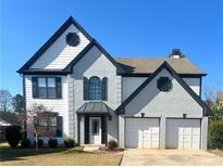 Two-story house with gray and white exterior, two-car garage, and landscaping at 2897 Hutchins Walk Ct, Snellville, GA 30078