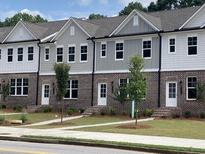 Three-story townhomes with brick and siding exteriors, showcasing modern design at 1280 Ainsworth Aly # 53, Sugar Hill, GA 30518