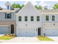 Two story townhome with white brick exterior, two-car garage, and landscaping at 695 Sunstone Ln, Lawrenceville, GA 30043