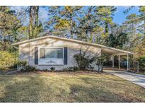 Brick ranch house with carport, well-manicured lawn, and mature trees at 4404 Mercer Rd, Decatur, GA 30035