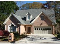 Brick house with gray roof, attached garage, and manicured landscaping at 2813 Livsey Woods Dr, Tucker, GA 30084