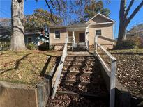 Tan house with steps leading to the front porch, surrounded by trees and leaves at 1480 Belmont Sw Ave, Atlanta, GA 30310