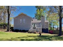 Gray house with deck, green lawn, and mature trees in the backyard at 2193 Hampton Se Trl, Conyers, GA 30013